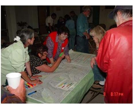 Residents gather around maps to identify wildfire hazard areas at a community meeting in Illinois Valley.